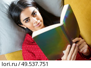 Persian woman at home reading on a couch wearing pyjamas. Persian woman at home reading on a couch. Стоковое фото, агентство Ingram Publishing / Фотобанк Лори