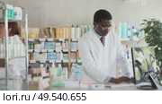 African American male pharmacist employee using computer. Assistant in background. Стоковое видео, видеограф Яков Филимонов / Фотобанк Лори
