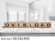 Sign with the word overload in a bright office environment on a wooden table. Стоковое фото, агентство Ingram Publishing / Фотобанк Лори