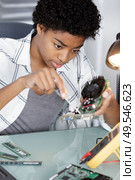 female repairwoman disassembling smartphone with screwdriver. Стоковое фото, агентство Ingram Publishing / Фотобанк Лори
