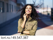 Arab woman with curly hair moved by the wind in urban background. Arab woman with curly hair moved by the wind. Стоковое фото, агентство Ingram Publishing / Фотобанк Лори