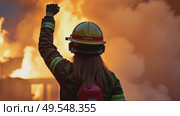 A woman in a firefighter's uniform raises her right arm in a fist pump after successful rescuing someone from a burning building. She signals her colleagues to start extinguishing the fire. Стоковое AI-видео, аниматор Sergey Grishin / Фотобанк Лори