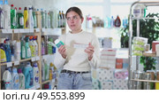 Girl housewife in household store examines package, chooses products toothpaste and related products. Стоковое видео, видеограф Яков Филимонов / Фотобанк Лори