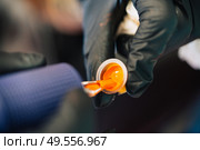 Tattoo woman loading the tattoo machine with orange ink. Tattoo concept.. Tattoo woman loading the tattoo machine with ink. Стоковое фото, агентство Ingram Publishing / Фотобанк Лори