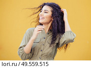 Arab woman with curly hair moved by the wind in urban background. Arab woman with curly hair moved by the wind. Стоковое фото, агентство Ingram Publishing / Фотобанк Лори