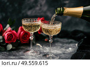 Champagne and red pink roses on a black concrete background. Copy space for text. Valentines drinks for for a pair of lovers. Bartender pours prosecco sparkling wine into glasses. Romance. Wedding Day. Стоковое AI-изображение, AI-художник Марина Демидюк / Фотобанк Лори