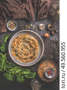 Tasty stuffed savory pastry pie with phyllo dough in traditional baking pan on dark rustic background with ingredients.  Top view. Balkan or oriental cuisine. Home cooking. Burek making. Ramadan food. Стоковое фото, агентство Ingram Publishing / Фотобанк Лори