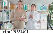 Concerned expecting woman attentively reviewing sunscreen bottle for UV protection and safe ingredients, checking for allergens or irritants, while pharmacist offering guidance in pharmacy. Стоковое видео, видеограф Яков Филимонов / Фотобанк Лори