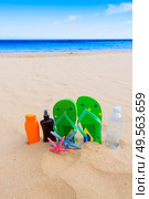 sandals and  bottle of water and suntan creams on sandy beach by sea side. Стоковое фото, агентство Ingram Publishing / Фотобанк Лори
