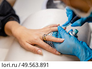 Close-up of Beautician painting her client’s nails in blue and yellow nail varnish in a beauty centre. Close-up of Beautician painting her client’s nails in blue and yellow nail varnish. Стоковое фото, агентство Ingram Publishing / Фотобанк Лори
