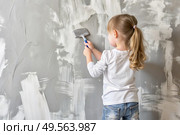 A little girl paints a wall in a new house. Interior decoration of the house, wall painting. Cosmetic repairs. Child labor. Стоковое AI-изображение, AI-художник Photojuli / Фотобанк Лори