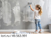A little girl paints a wall with a paint roller in a new house. Interior decoration of the house, wall painting. Cosmetic repairs. Child labor. Стоковое AI-изображение, AI-художник Photojuli / Фотобанк Лори