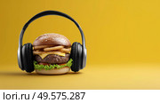 Unique hamburger wearing headphones in vibrant yellow setting. Стоковое AI-изображение, AI-художник Katsiaryna Repich / Фотобанк Лори