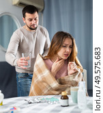 Woman suffering from flu sitting at home while husband taking care of her. Стоковое фото, фотограф Яков Филимонов / Фотобанк Лори