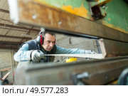 middle-aged male operative working with sheet metal viewed through machine. Стоковое фото, агентство Ingram Publishing / Фотобанк Лори