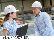 Conversing man and woman wearing hardhats. Стоковое фото, агентство Ingram Publishing / Фотобанк Лори