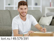 young man holding cardbox indoors. Стоковое фото, агентство Ingram Publishing / Фотобанк Лори