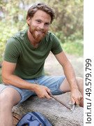 male hiker hands sharpen stick with knife on the ground. Стоковое фото, агентство Ingram Publishing / Фотобанк Лори