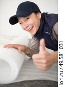 woman unrolling underlay over floor surface. Стоковое фото, агентство Ingram Publishing / Фотобанк Лори
