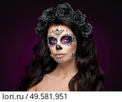 Portrait of a woman with sugar skull makeup over red background. Halloween costume and make-up. Portrait of Calavera Catrina. Стоковое фото, агентство Ingram Publishing / Фотобанк Лори