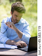 man sitting at wooden desk inside garden working on computer. Стоковое фото, агентство Ingram Publishing / Фотобанк Лори