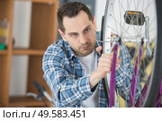 man fixing wheel on a bicycle. Стоковое фото, агентство Ingram Publishing / Фотобанк Лори