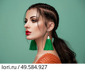 Brunette girl with perfect makeup. Beautiful model woman with curly hairstyle. Care and beauty hair products. Lady with braided hair. Model with jewelry. Turquoise background. Стоковое фото, агентство Ingram Publishing / Фотобанк Лори