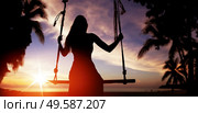Woman’s silhouette sitting on a seesaw and looking at sunset. Стоковое фото, агентство Ingram Publishing / Фотобанк Лори