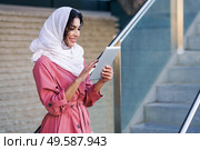 Young Arab woman wearing hijab headscarf using digital tablet in business environment.. Young Muslim woman wearing hijab using digital tablet outdoors. Стоковое фото, агентство Ingram Publishing / Фотобанк Лори