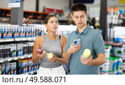 Spouses scans product QR code with phone on color aerosol in paint and vanish store. Стоковое фото, фотограф Яков Филимонов / Фотобанк Лори