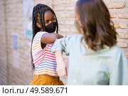 Multiethnic young women wearing masks greeting at each other with their elbows outdoors. Multiethnic young women wearing masks greeting at each other with their elbows. Стоковое фото, агентство Ingram Publishing / Фотобанк Лори
