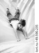 Smiling little boy playing on inflatable slide, looking at camera, black and white shot. Smiling little boy playing on inflatable slide. Стоковое фото, агентство Ingram Publishing / Фотобанк Лори