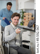 disabled young man in wheelchair opens the oven. Стоковое фото, агентство Ingram Publishing / Фотобанк Лори