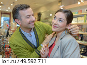 man attaching necklace to girls neck in retail store. Стоковое фото, агентство Ingram Publishing / Фотобанк Лори