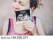 Woman holding the ultrasound of her baby. Стоковое фото, агентство Ingram Publishing / Фотобанк Лори