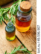 Essential oil bottle with fresh rosemary. Bottle glass of essential rosemary extract. Rosemary in herbal medicine. Стоковое фото, агентство Ingram Publishing / Фотобанк Лори