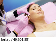 Doctor painting the area of a middle-aged woman’s face where the PDO suture treatment threads will be injected.. Doctor painting the area of a woman’s face where the PDO suture treatment threads will be injected. Стоковое фото, агентство Ingram Publishing / Фотобанк Лори