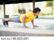 Black man doing triceps dip exercise on city street bench. Fitness, sport, exercising, training and people concept. Black man doing triceps dip exercise on city street bench. Стоковое фото, агентство Ingram Publishing / Фотобанк Лори