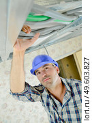Builder holding cables at ceiling level. Стоковое фото, агентство Ingram Publishing / Фотобанк Лори