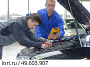 auto mechanic teacher and trainee performing tests at mechanic school. Стоковое фото, агентство Ingram Publishing / Фотобанк Лори