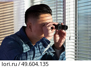 young man looking through a glass window with binoculars. Стоковое фото, агентство Ingram Publishing / Фотобанк Лори