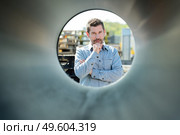 worker looking through a pipes outside a factory. Стоковое фото, агентство Ingram Publishing / Фотобанк Лори