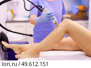Woman receiving legs laser hair removal at a beauty center. Laser depilation treatment in an aesthetic clinic.. Woman receiving legs laser hair removal at a beauty center. Стоковое фото, агентство Ingram Publishing / Фотобанк Лори