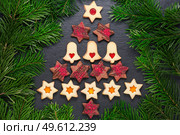 Christmas tree from homemade linzer cookies with raspberry jam and chocolate stars with raspberry crunches on slate table with pine branches. Christmas tree from homemade cookies on slate table with pine branches. Стоковое фото, агентство Ingram Publishing / Фотобанк Лори