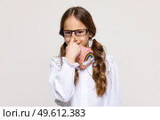 Headshot of a little school geek girl adjusting her nerdy glasses on white background. Copy space. Back to school concept. Стоковое фото, фотограф Ирина Михайличенко / Фотобанк Лори