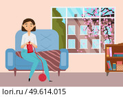 A young girl is engaged in knitting at home. Beautiful female character makes warm clothes with pleasure while sitting in a chair by the window. Person is engaged in a hobby during her free time. Young girl is engaged in knitting. Woman having fun making warm clothes while sitting on an armchair. Стоковая иллюстрация, агентство Ingram Publishing / Фотобанк Лори