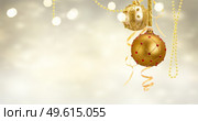 Golden christmas balls garland and evergreen fir tree on glowing golden background banner. Golden christmas balls. Стоковое фото, агентство Ingram Publishing / Фотобанк Лори