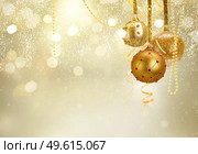 Golden christmas balls garland and evergreen fir tree on glowing golden background with copy space. Golden christmas balls. Стоковое фото, агентство Ingram Publishing / Фотобанк Лори