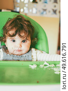 Baby eating food in her green highchair. Стоковое фото, агентство Ingram Publishing / Фотобанк Лори