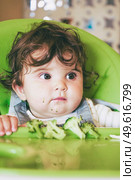 Baby eating food in her green highchair. Стоковое фото, агентство Ingram Publishing / Фотобанк Лори